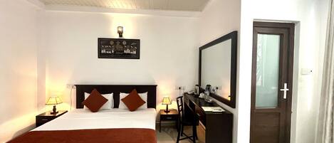 Una habitación de hotel con cama, escritorio, espejo y puerta.