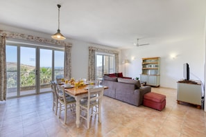 A spacious living area with a dining table, sofa, and a TV stand. - Ta Frenc Apartments (Ghasri)