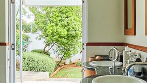 A bathroom with a large window, a bathtub, and a sink. - Maison Jacaranda (Randburg)