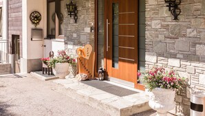 A stone facade with a wooden door, a welcome sign, and two potted plants. - Pension Roetelstein (Ramsau am Dachstein)