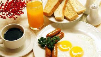 Un plato de desayuno con salchichas, huevos, tostadas y un vaso de jugo de naranja.