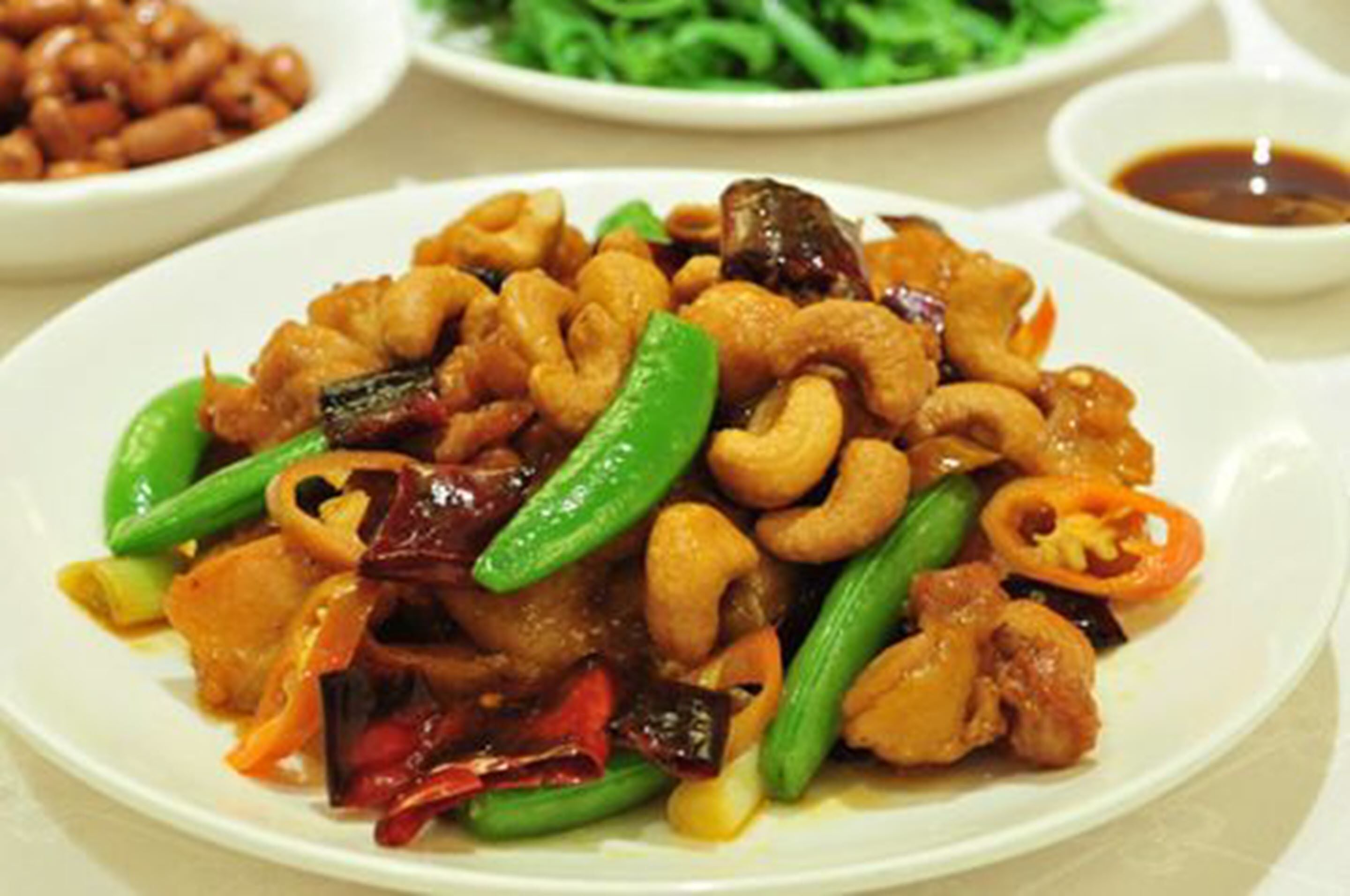 A plate of stir-fried food with cashews, green peppers, and other vegetables.