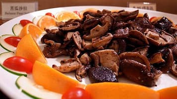 A plate of cooked mushrooms and sliced fruits.