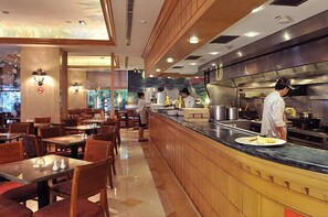 Un restaurante moderno con mobiliario de madera, una barra de mármol y un chef preparando comida.