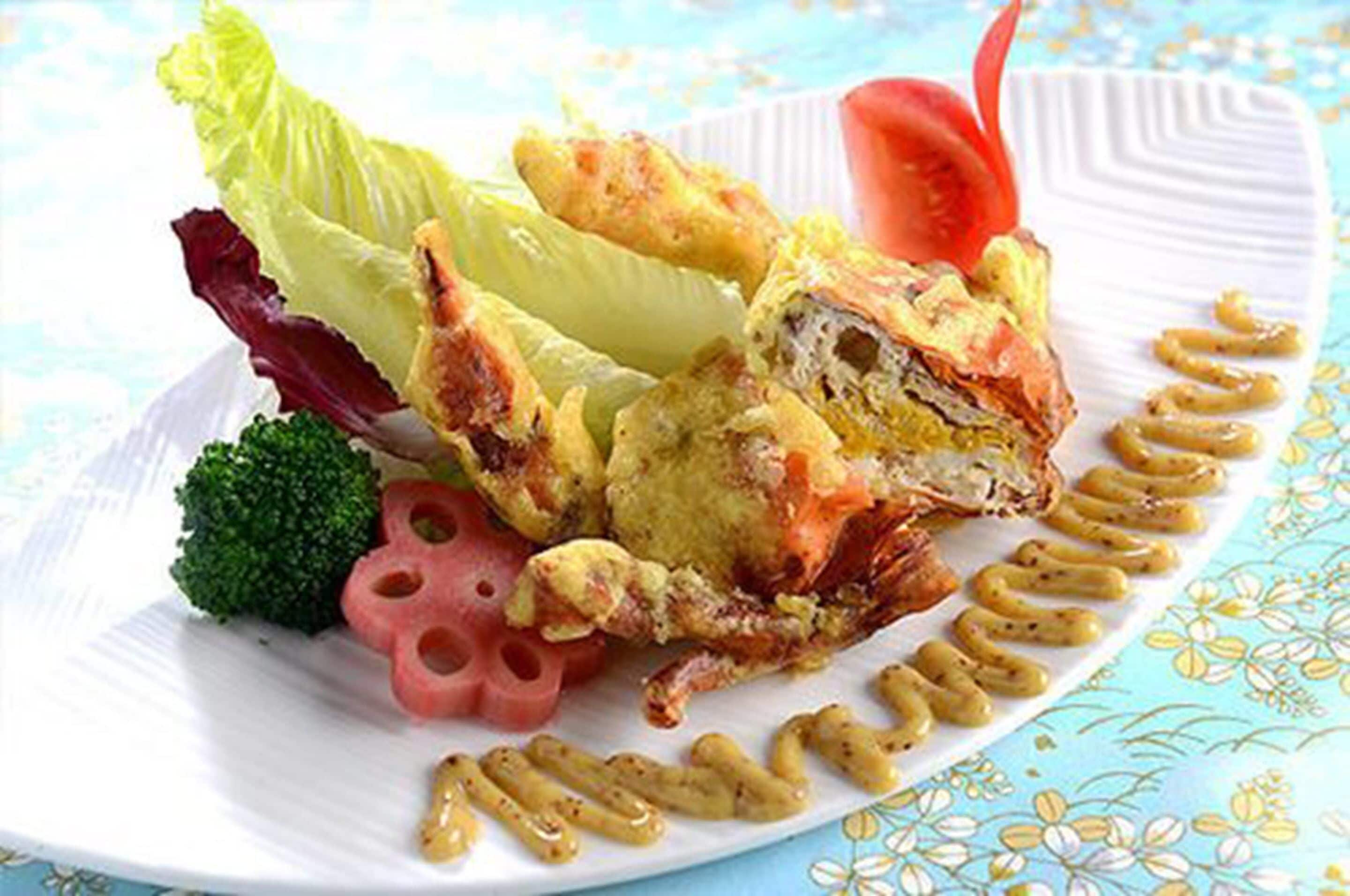 A plate with fried food, vegetables, and a sauce.