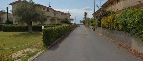 A residential street with houses on either side, a clear sky, and a road leading towards the horizon.