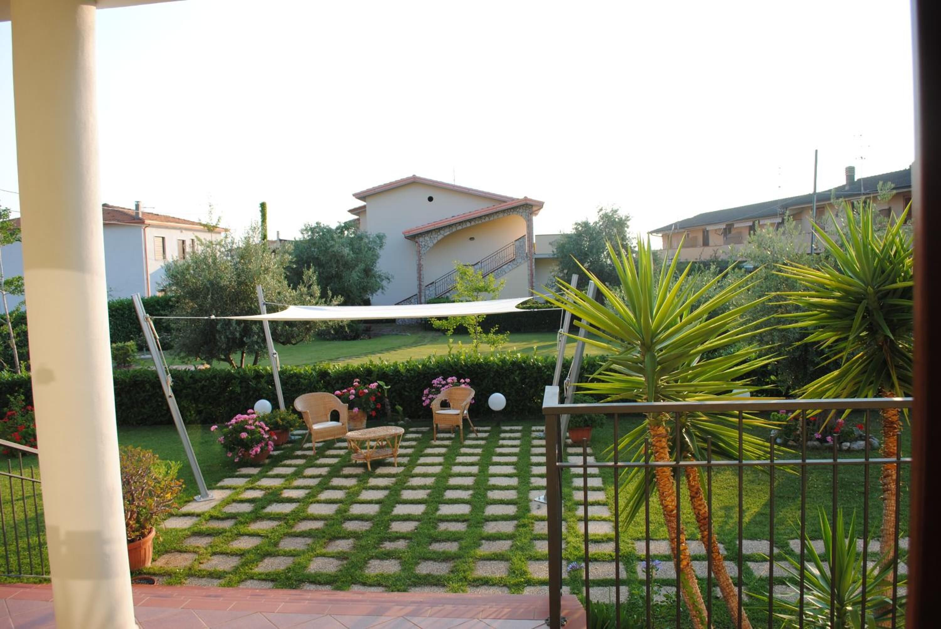 A patio with a swing set, a small seating area, and a garden with a lawn and potted plants.