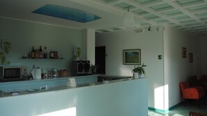 Una cocina con microondas, tostadora y varios utensilios de cocina sobre la encimera. El techo presenta un diseño azul y una lámpara colgante.