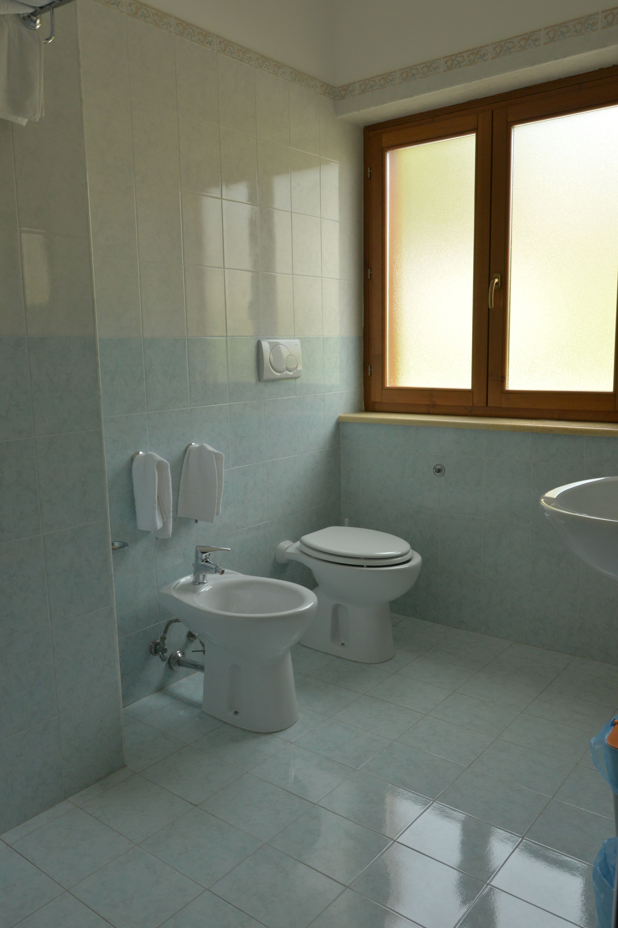 A bathroom with a toilet, bidet, and sink.