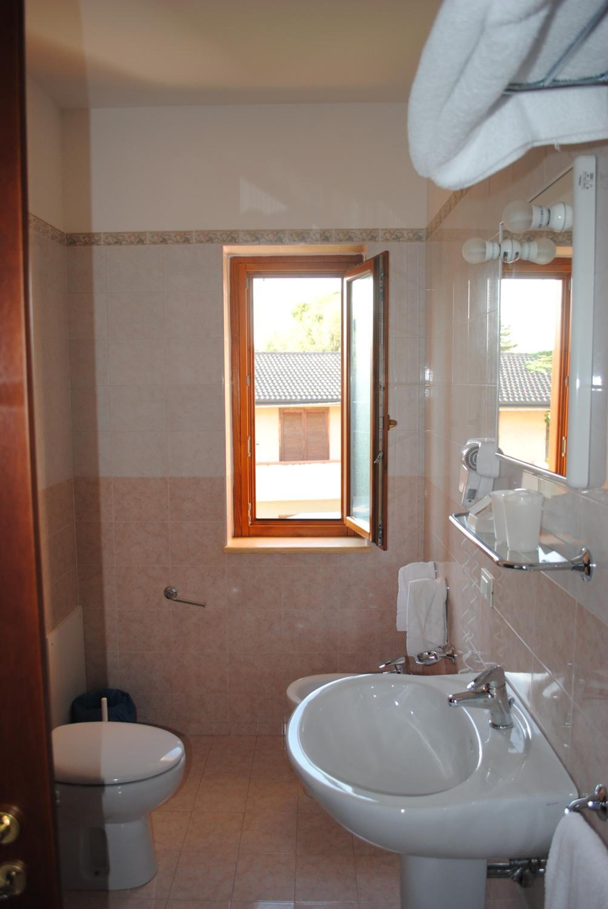 Un baño con inodoro, lavamanos y ventana que ofrece vistas al exterior.