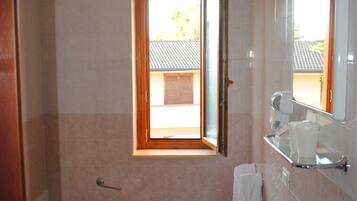 Un baño con inodoro, lavamanos y ventana que ofrece vistas al exterior.