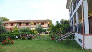 A courtyard with a lawn, potted plants, and a building with balconies.