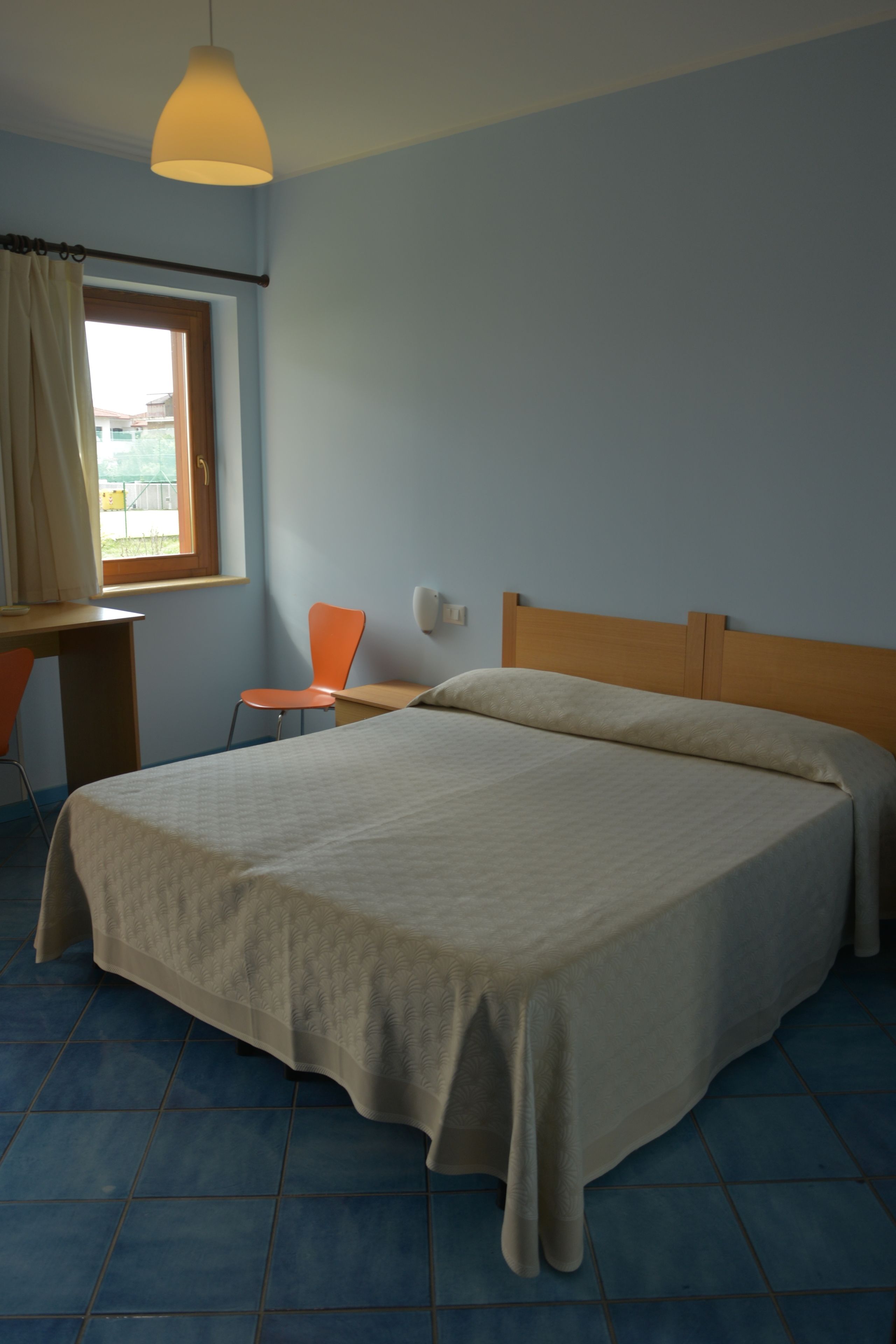A bedroom with a bed, a desk, and a chair.
