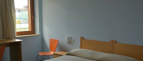 Un dormitorio con cama, escritorio y silla.