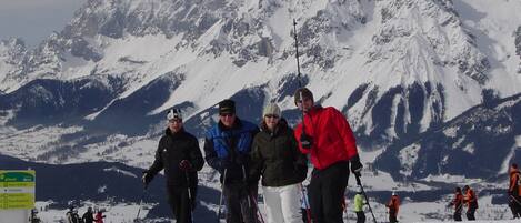 A group of people on skis on a snowy mountain with a sign indicating ski trails.