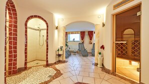 A hotel bathroom with a shower, seating area, and a wooden door.