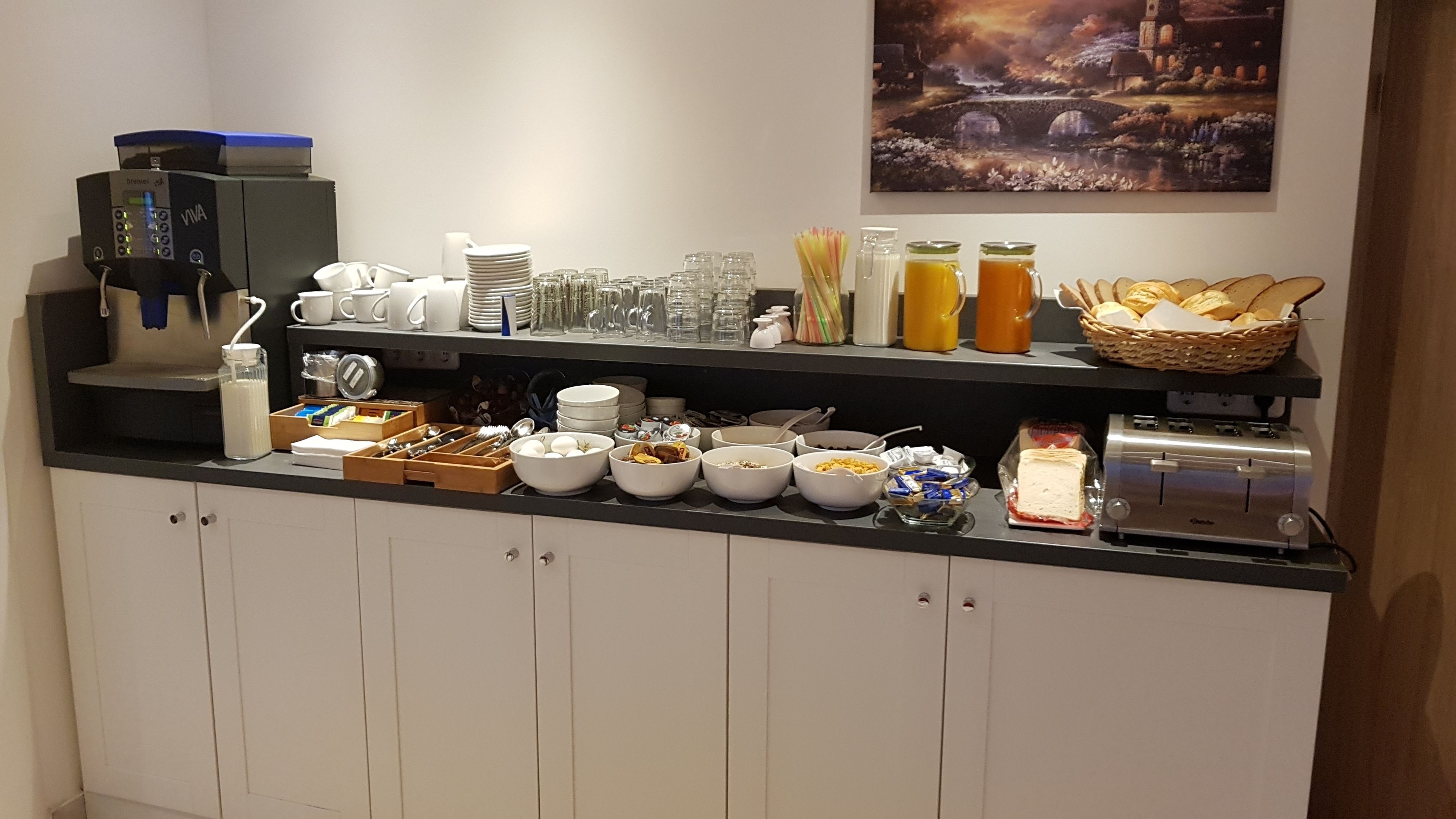 Ein reichhaltiges Frühstücksbuffet mit Speisen, Geschirr und einer Kaffeemaschine.