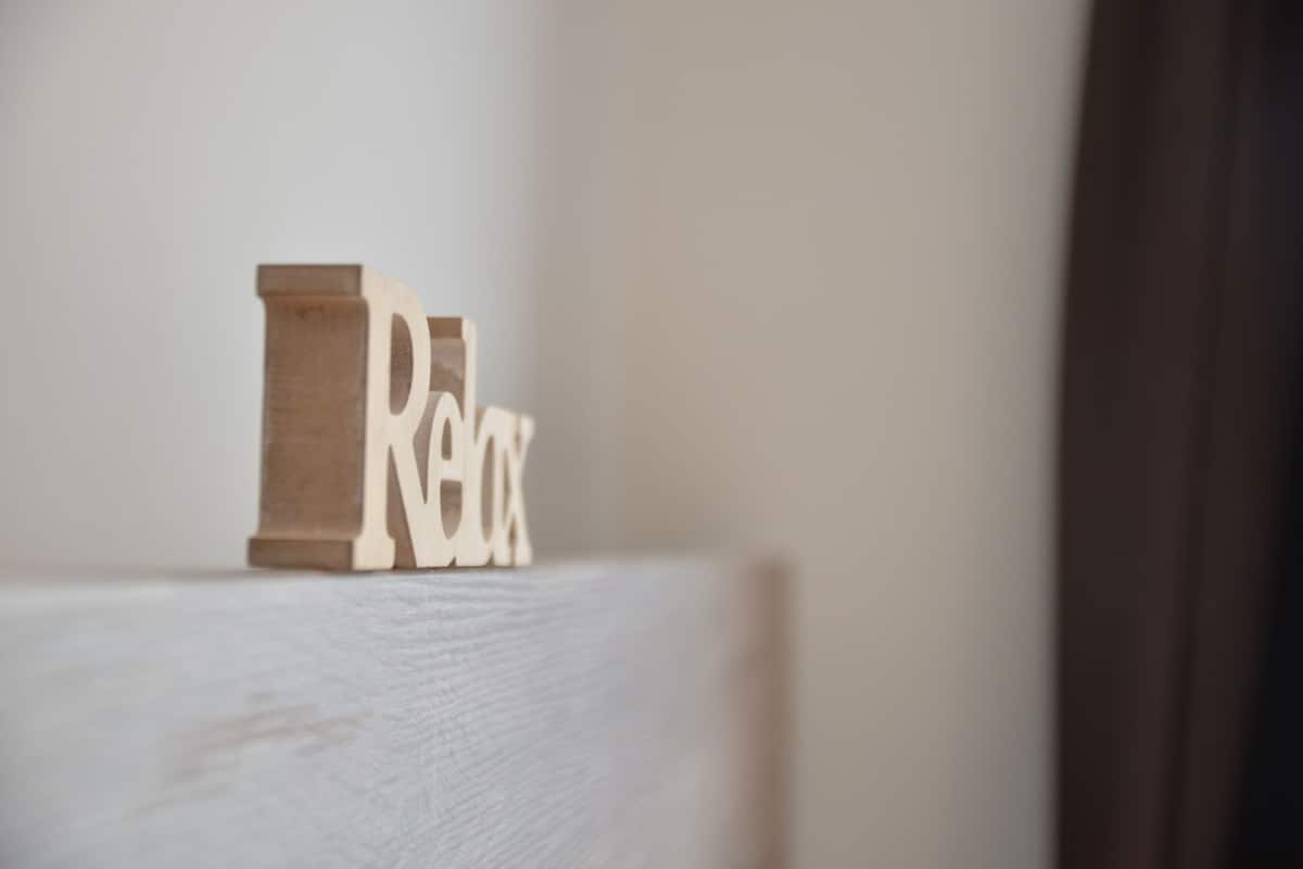Ein Holzklotz mit dem Wort 'Relax' auf einer weißen Fläche.