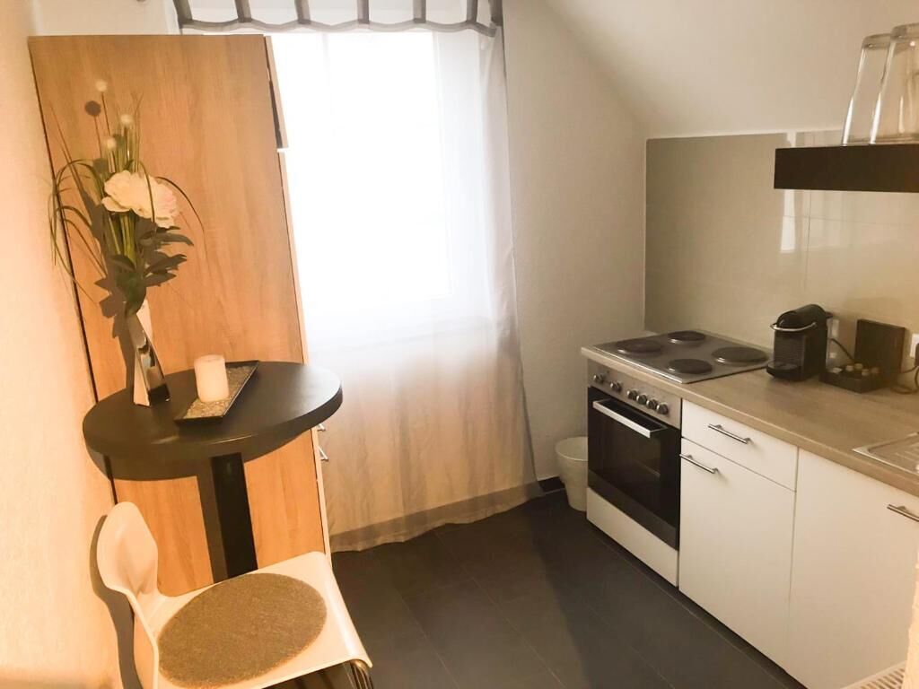 A compact kitchen with a stove, oven, and a small dining area with a chair and table.