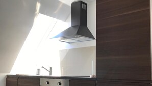 Una cocina moderna con horno empotrado, extractor de acero inoxidable y ventana sobre el fregadero.
