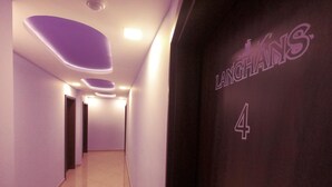 Un pasillo con diseño moderno, con un techo iluminado en morado y una puerta con la leyenda 'LANGHANS 4'.