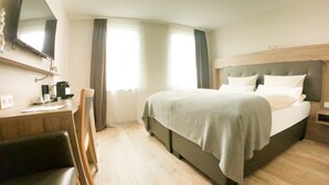 Una habitación de hotel con una cama, un escritorio, una silla y un televisor.