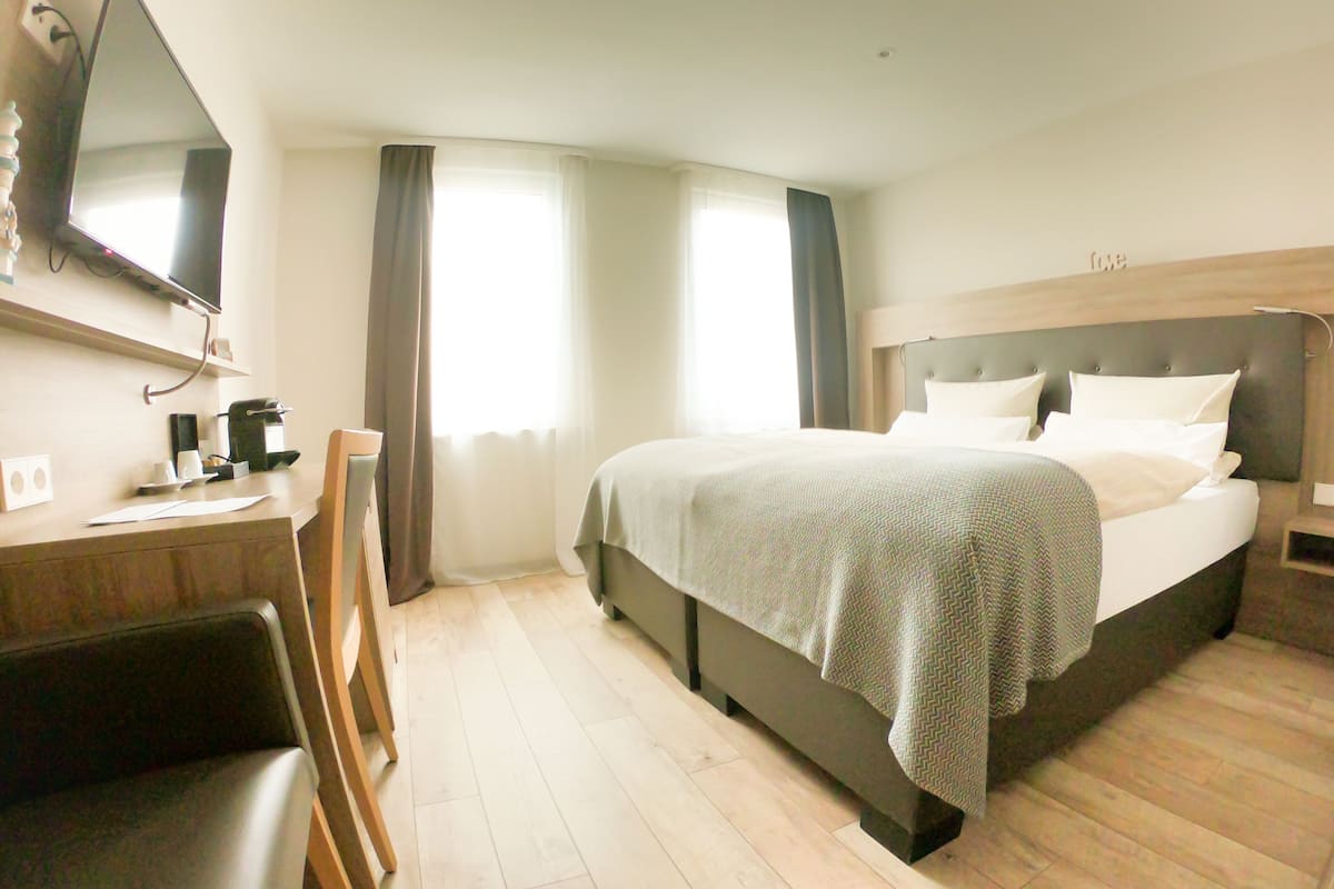 Ein Hotelzimmer mit Bett, Schreibtisch, Stuhl und Fernseher.