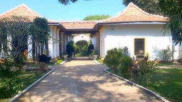 A building with a tiled roof and a central archway, surrounded by greenery.