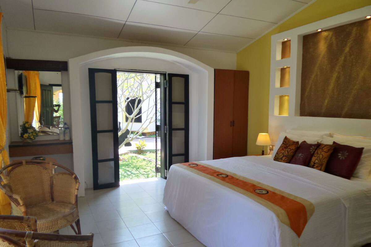 A hotel room with a bed, a chair, a desk, and a view of the outside.