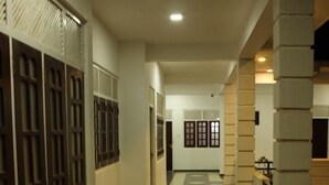 A hallway with a tiled floor, white walls, and wooden doors with glass panels. - Hotel senora kataragama (Kataragama)