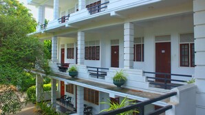 A multi-story building with a white facade, multiple balconies, and red doors. - Hotel senora kataragama (Kataragama)