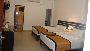 A hotel room with two beds, a ceiling fan, an air conditioning unit, a bedside lamp, and a door leading to a bathroom. - Hotel senora kataragama (Kataragama)
