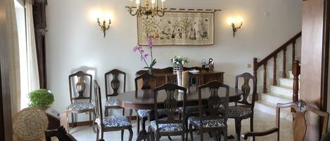 A dining area with a chandelier, patterned chairs, and a staircase.