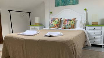 Una cama bien hecha con dos almohadas, una mesita de noche con una lámpara y una obra de arte colgada en la pared.