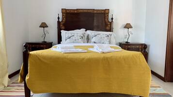 A neatly made bed with a yellow bedspread, two pillows with musical notes, and two bedside tables with lamps.