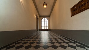 A hallway with a checkered floor, a large arched window at the end, and a wall-mounted cabinet. - La Porta del Paradiso (Florence)