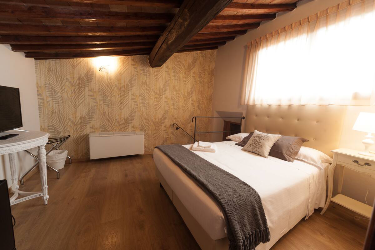 A bedroom with a bed, bedside table, lamp, and a radiator.