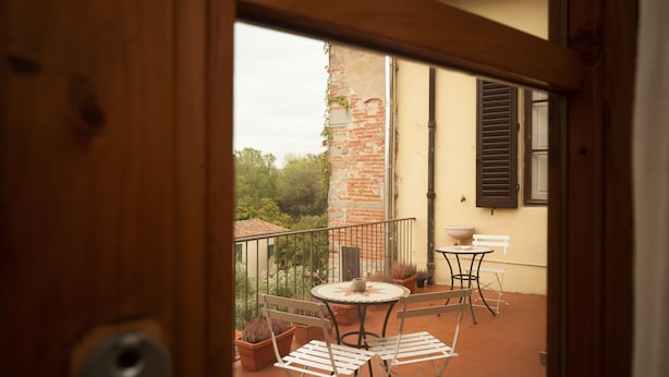 A balcony with a table and chairs, potted plants, and a brick wall. - La Porta del Paradiso (Florence)