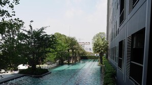 A modern building with a water feature in front, surrounded by greenery and a clear sky. - Sky Home at Bangkok-Bangna (Bangkok)