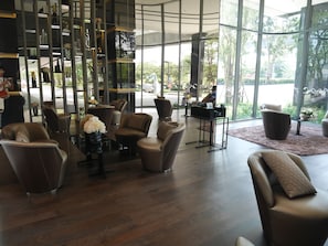 A modern interior with leather chairs, a glass display, and large windows offering a view of the outdoors.