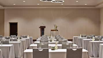 A conference room with tables set for a meeting, a podium, and a decorative vase with plants.