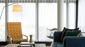 Ein modernes Wohnzimmer mit einem gelben Sessel, einem blauen Sofa und einem Couchtisch mit Büchern.