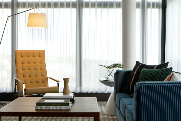 Una sala de estar moderna con un sillón amarillo, un sofá azul y una mesita de centro con libros.