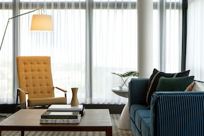 A modern living room with a yellow armchair, a blue sofa, and a coffee table with books.