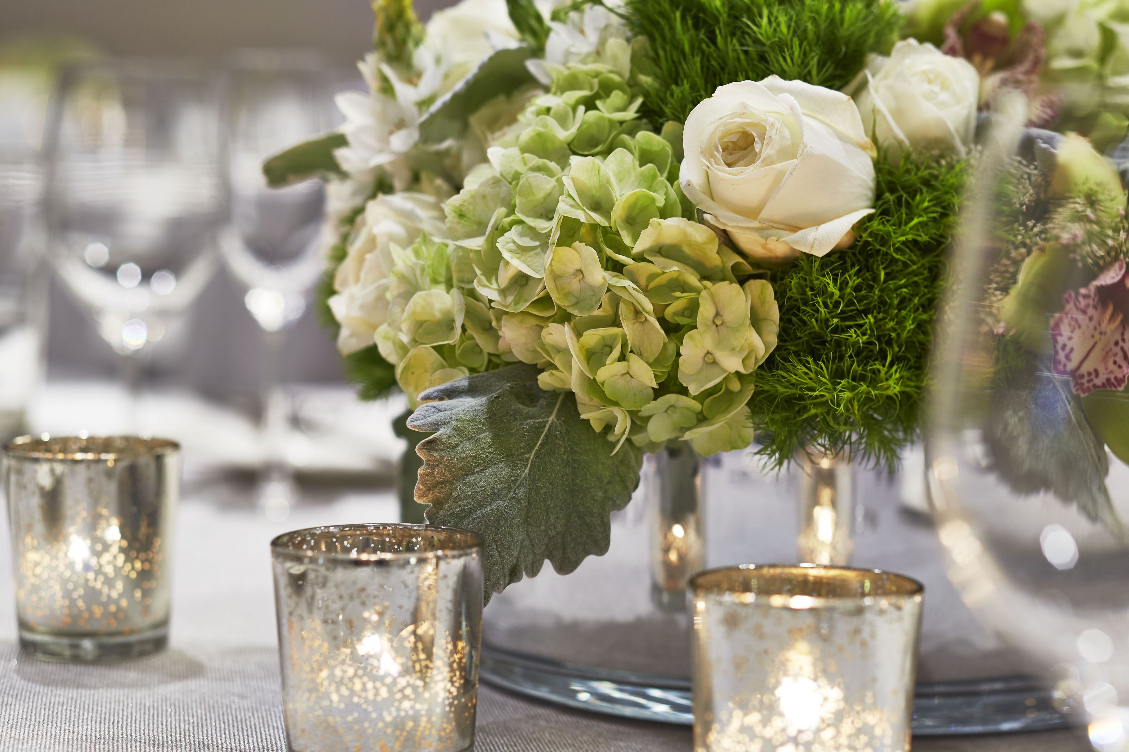 A table setting with a floral arrangement, candles, and a decorative leaf.