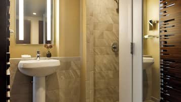 Een badkamer met een wit wastafelmeubel, een spiegel en een douchehoek.