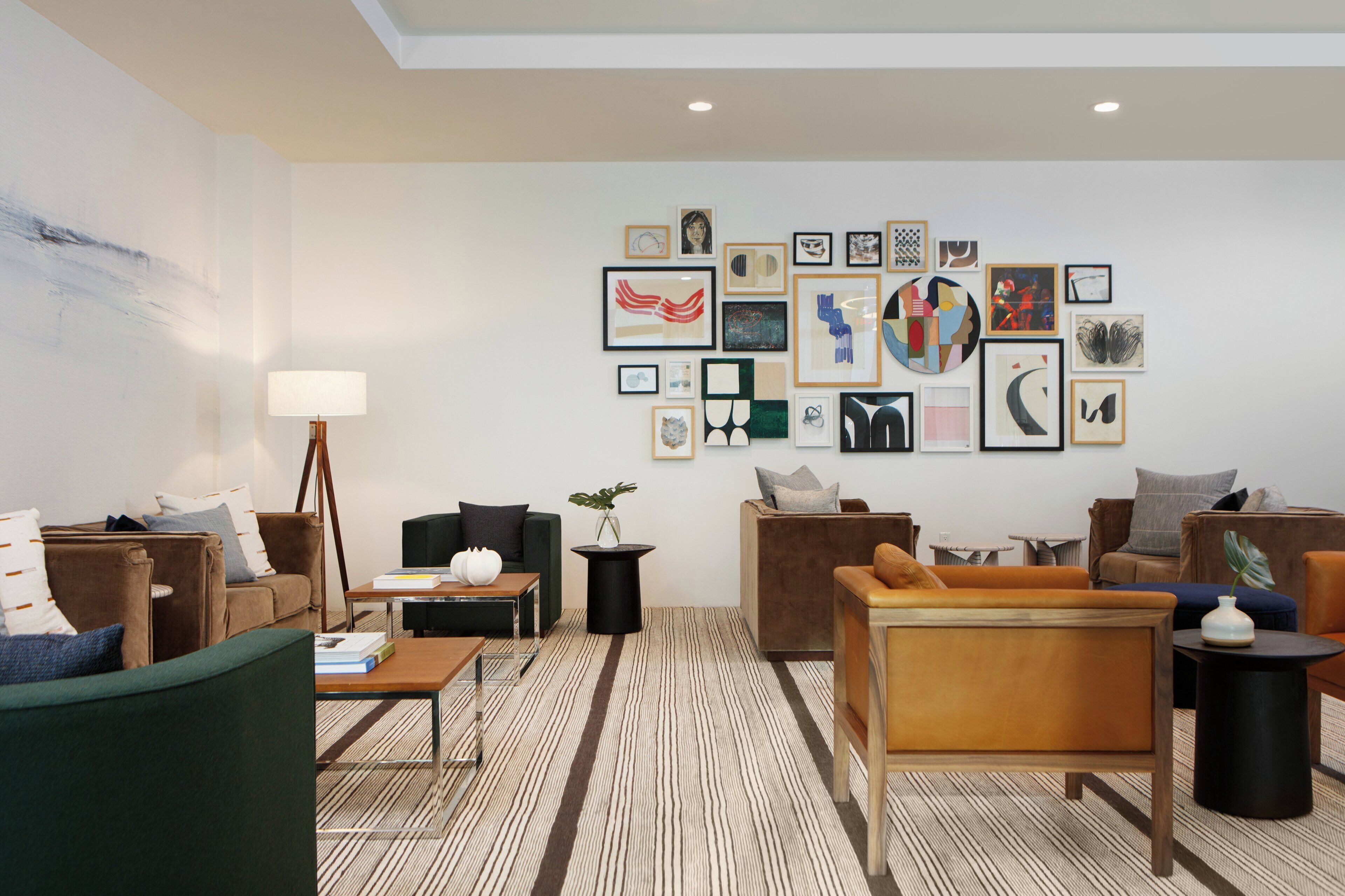 Un salón moderno con diferentes opciones de asiento, incluyendo sofás y sillones, dispuestos alrededor de una mesa de centro. Las paredes están decoradas con una colección de obras de arte enmarcadas.