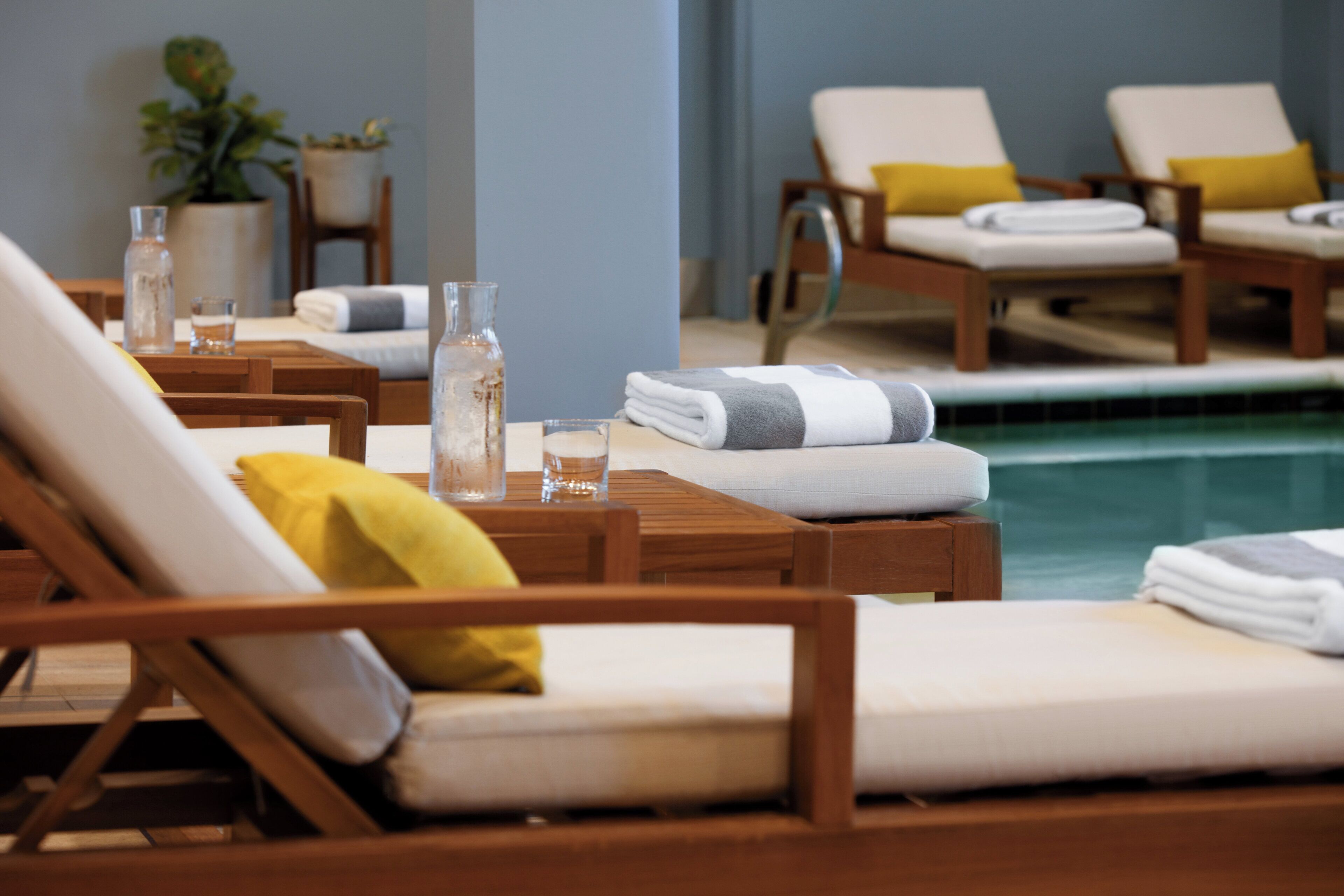 A poolside area with lounge chairs, towels, and glass bottles on tables.