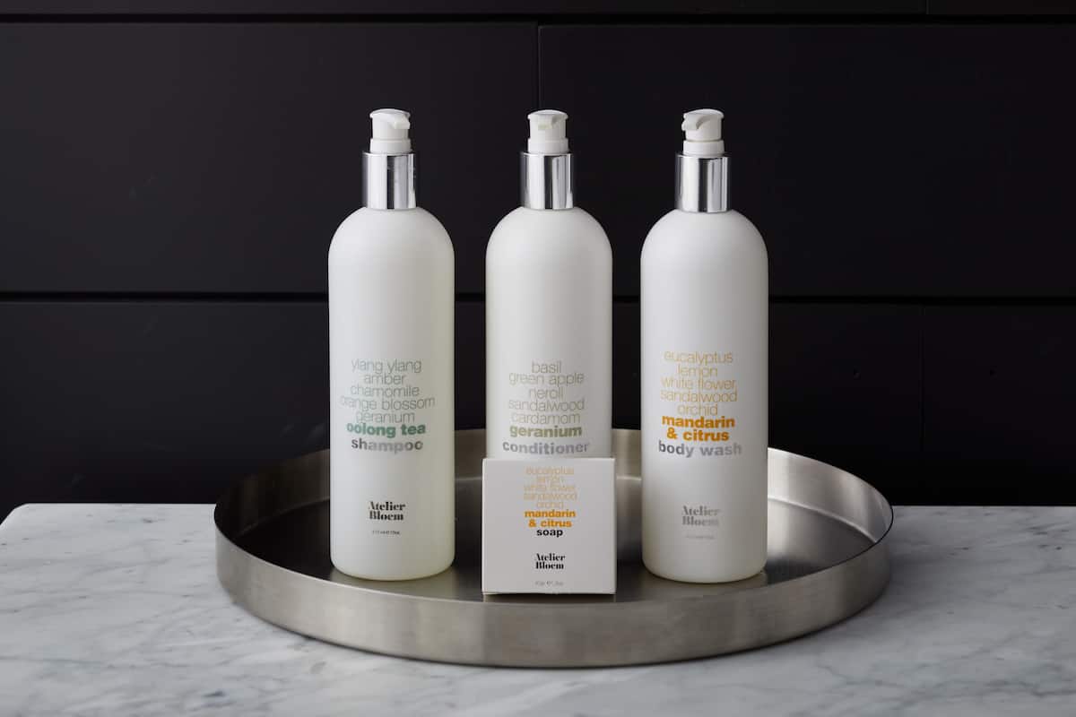Three bottles of Atelier Bloom products on a metallic tray.