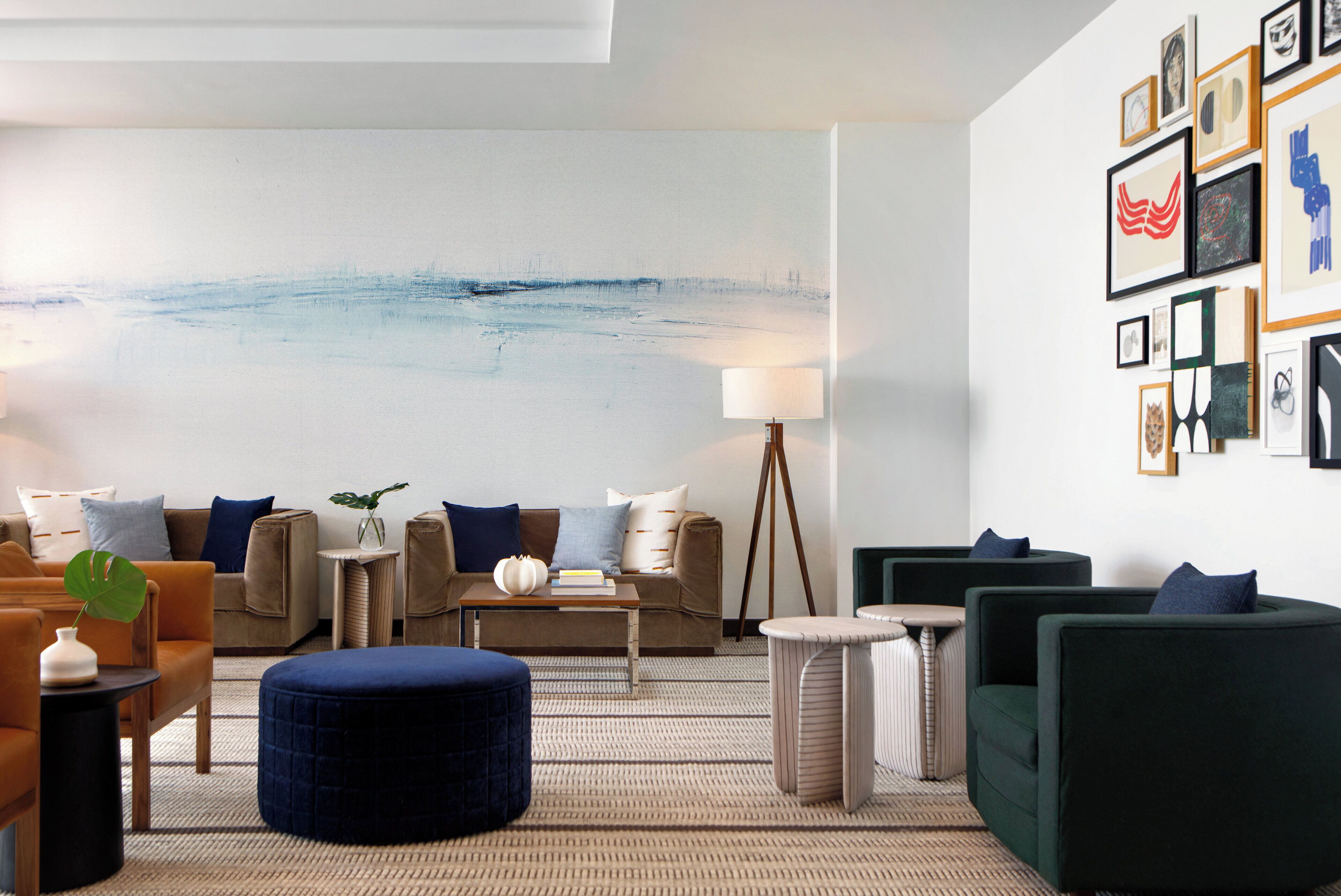 A modern living room with a large abstract painting, comfortable seating, and a variety of framed artworks on the walls.